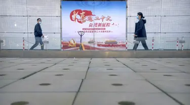 Orang-orang yang mengenakan masker melewati papan reklame yang menandai Kongres Nasional ke-20 Partai Komunis China yang akan datang, di Beijing, Selasa (11/10/2022). Kota-kota di China memberlakukan kembali lockdown dan pembatasan perjalanan. (AP Photo/Mark Schiefelbein)