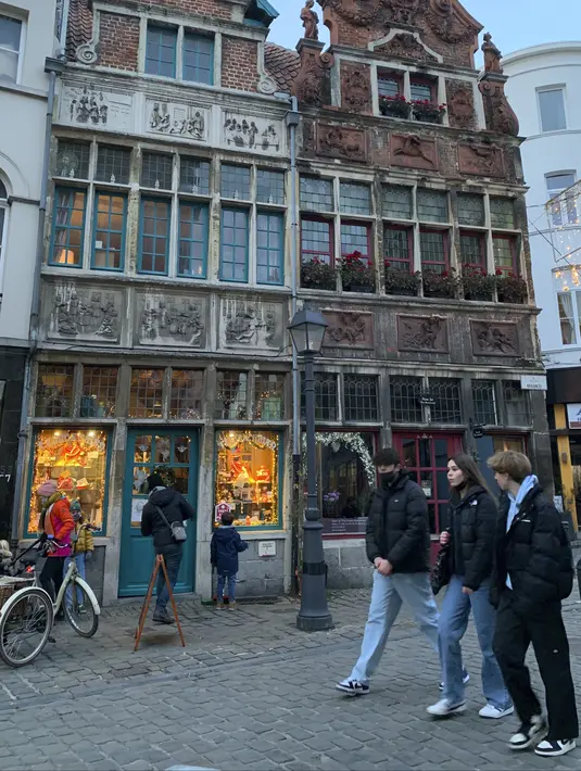 Orang-orang berjalan di kawasan shopping street di Ghent, Belgia, Rabu (22/12/2021). Mulai hari Minggu, pihak berwenang telah memutuskan menutup bioskop, teater dan ruang konser, sementara penggemar olahraga akan dilarang masuk stadion dan aula dalam ruangan. (AP Photo/Virginia Mayo)