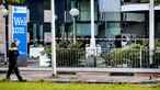 Seorang polisi berjalan dekat sebuah mobil van yang menabrak pintu depan gedung tempat surat kabar ternama Belanda, De Telegraaf di Amsterdam, Selasa (26/6). Akibatnya mobil van itu terbakar dan menyebakan kerusakan pada gedung. (KOEN VAN WEEL/ANP/AFP)
