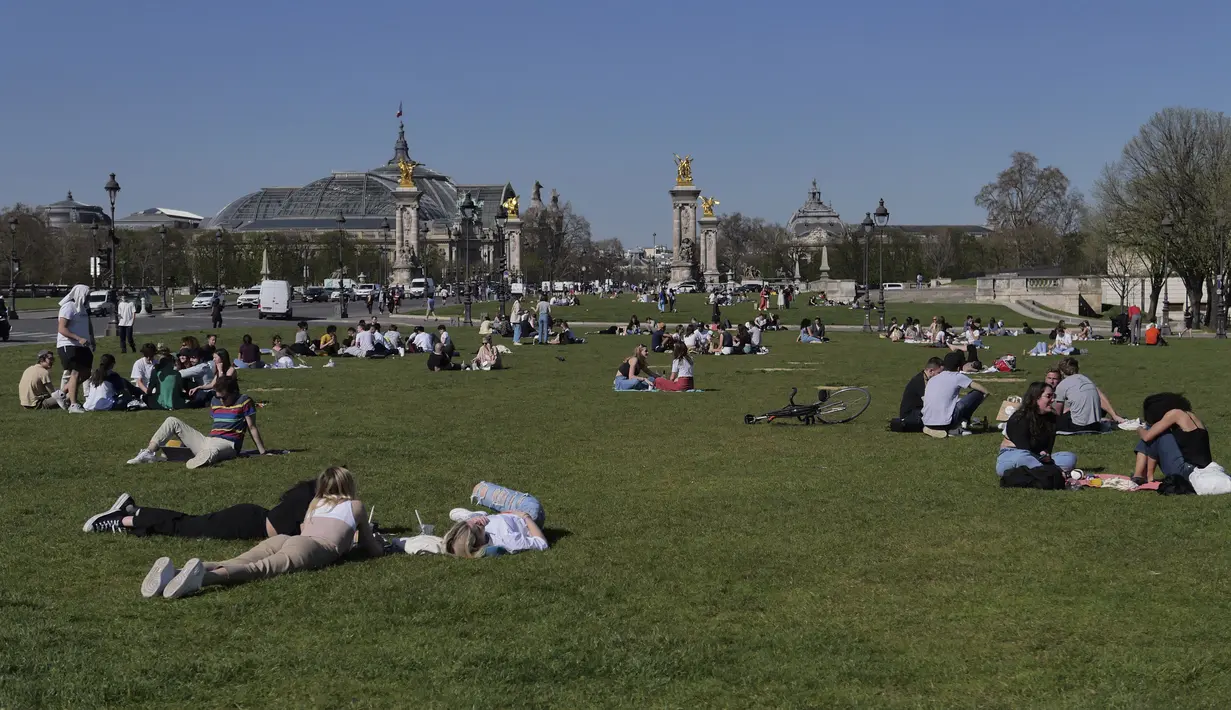 Orang-orang bersantai saat menikmati matahari di Esplanades des Invalides di Paris, Selasa (30/3/2021). Cuaca panas diperkirakan akan berlangsung selama beberapa hari di seluruh negeri. (AP Photo/Christophe Ena)