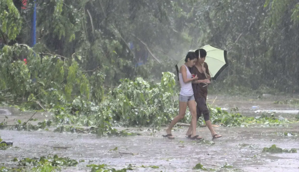 Beberapa warga mencoba melintas ditengah Topan Kalmaegi yang menerjang wilayah Qionghai di provinsi Hainan, Tiongkok, (16/9/2014). (REUTERS/Stringer)