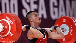 Atlet Indonesia, Rizki Juniansyah, berlaga pada cabang angkat besi 73 Kg putra SEA Games 2023 di Phnom Penh, Kamboja, Minggu (14/5/2022). Rizki tampil mengesankan dengan angkatan total 347 kg, terdiri dari 156 angkatan snatch dan 191 kg angkatan clean and jerk. (Bola.com/Abdul Aziz)