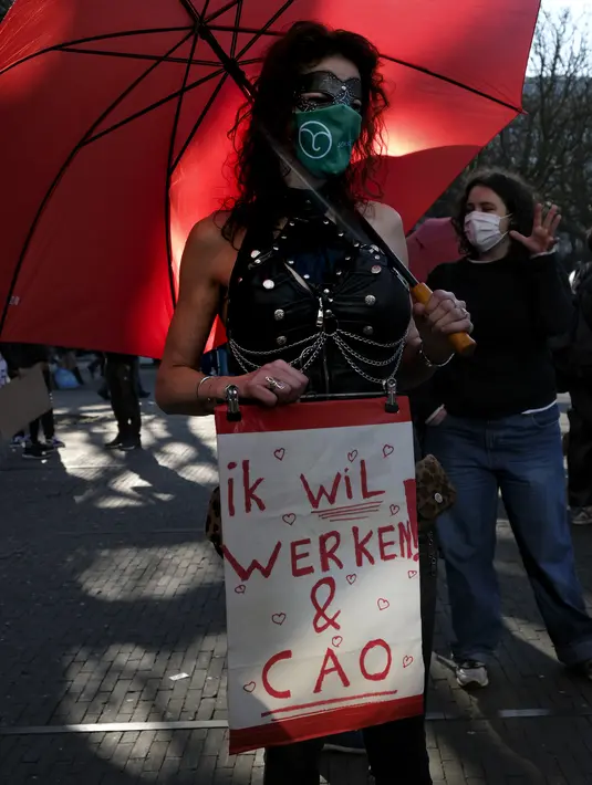 Seorang pekerja seks menuntut pekerjaan dan perjanjian kerja bersama ketika memprotes perlakuan dan stigma yang tidak setara saat demonstrasi di Den Haag, Belanda, Selasa (2/3/2021). Mereka berdemonstrasi di luar parlemen dalam protes terhadap penguncian keras virus corona oleh pemerintah. (AP Photo