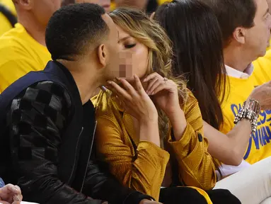 Penyanyi, John Legend bersama sang istri Chrissy Teigan terlihat berciuman saat menonton pertandingan final NBA 2016 antara Golden State Warriors dan Cleveland Cavaliers di Oracle Arena, California, USA (2/6/2016). (Kyle Terada-USA TODAY Sports)