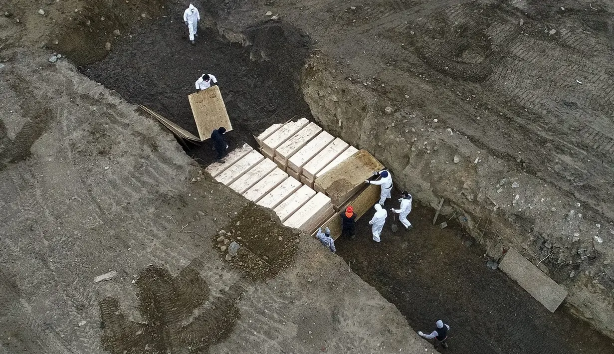 Pekerja yang mengenakan alat pelindung diri mengubur jenazah dalam parit di Pulau Hart, Bronx, New York, Amerika Serikat, Kamis (9/4/2020). Sebelum menjadi tempat pemakaman korban virus corona COVID-19, Pulau Hart lebih dari 150 tahun menjadi kuburan massal. (AP Photo/John Minchillo)