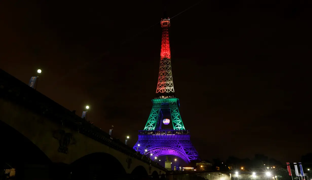 Lampu berwarna pelangi menerangi Menara Eiffel di Paris pada Senin (13/6/2016)  malam. Menara yang terkenal dengan romantisme itu memberikan penghormatan untuk korban penembakan brutal di klub malam gay di Orlando, Florida AS. (Thomas SAMSON/AFP)