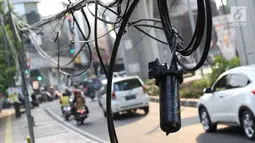 Instalasi kabel menjuntai ke trotoar di Jalan Kyai Maja, Jakarta, Rabu (10/4). Selain menganggu kenyamanan pejalan kaki, kondisi instalasi kabel yang semrawut tersebut juga berbahaya apabila mengandung aliran listrik. (Liputan6.com/Immanuel Antonius)