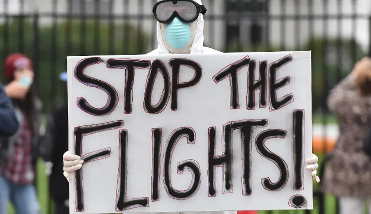 Jeff Hulbert dari Annapolis, mengenakan baju pelindung dan masker sambil membawa poster menuntut penghentian semua penerbangan dari Afrika Barat terkait virus Ebola, di luar Gedung Putih, Washington DC, 16 Oktober 2014. (AFP PHOTO/MLADEN ANTONOV)