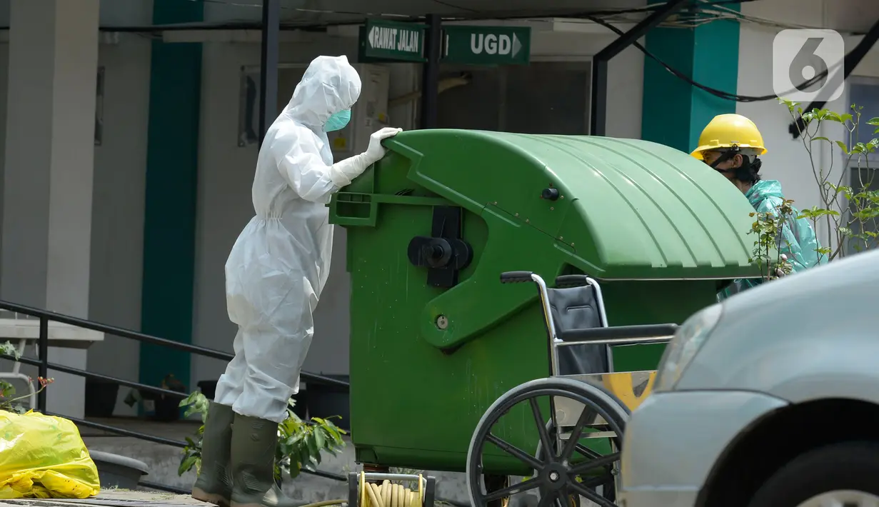 Petugas kesehatan memakai baju APD sedang membersihkan sampah bekas medis di Puskesmas Pamulang, Kecamatan Pamulang, Tangerang Selatan, Banten, Senin (13/04/2020). Sampah bekas medis tes Covid-19 tersebut akan dimusnahkan guna untuk mensteril kawasan puskesmas. (merdeka.com/Dwi Narwoko)