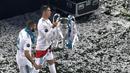 Pemain Real Madrid, Cristiano Ronaldo (kanan) membawa trofi Liga Champions 2017/2018 bersama rekannya Karim Benzema saat merayakan kemenangan di Stadion Santiago Bernabeu, 27 Mei 2018. (AFP/Gabriel Bouys)