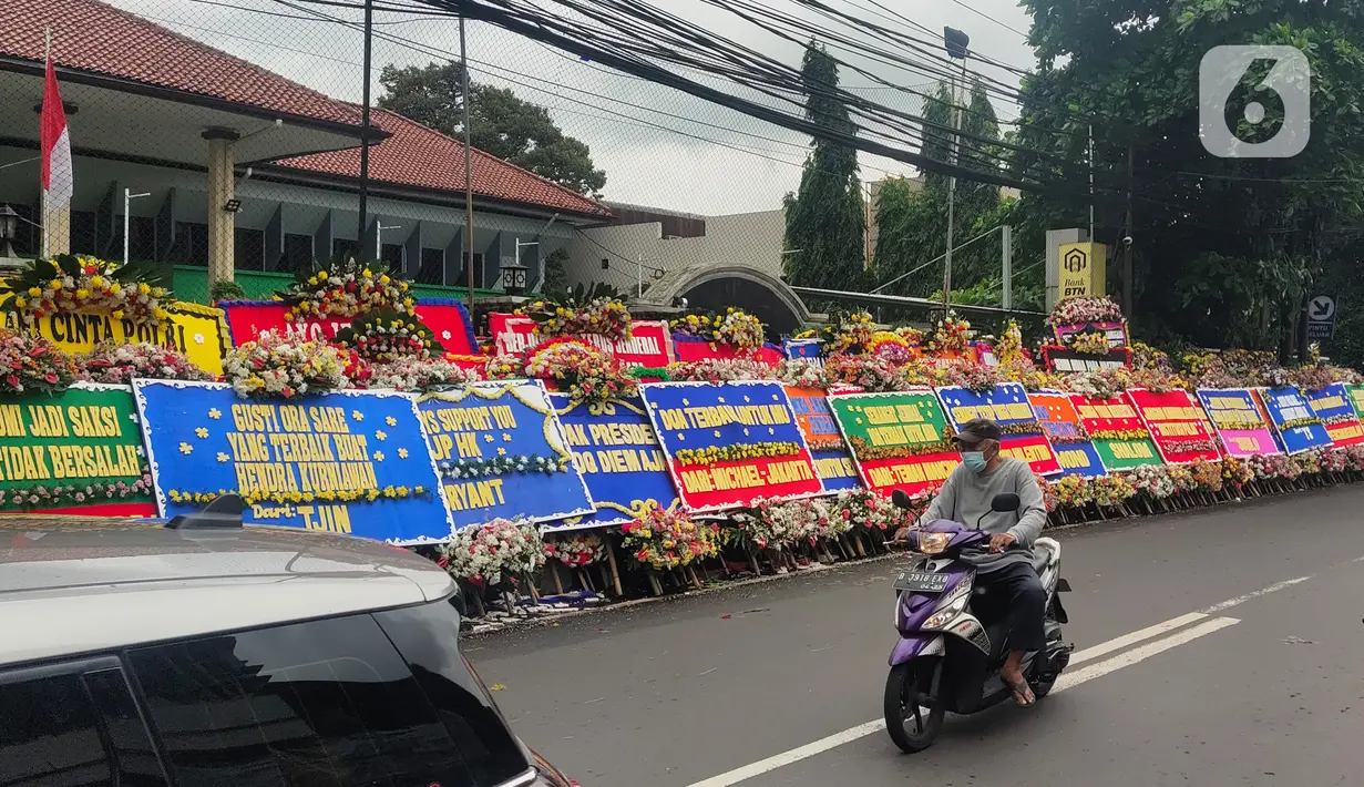 Pengendara melintasi karangan bunga untuk terdakwa Hendra Kurniawan di depan Pengadilan Negeri Jakarta Selatan, Senin (27/2/2023). Berbagai ucapan serta dukungan datang dari sejumlah elemen masyarakat untuk Hendra Kurniawan akan menjalani sidang vonis kasus perintangan penyidikan kematian Nofriansyah Yosua Hutabarat alias Brigadir J. (Liputan6.com/Angga Yuniar)