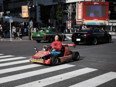 Seorang wanita mengendarai go-kart di persimpangan Shibuya di Tokyo, Jepang (23/5/2019). Shibuya adalah salah satu distrik khusus kota Tokyo, Jepang. Distrik kota ini didirikan pada 15 Maret 1947. (AFP Photo/Behrouz Mehri)