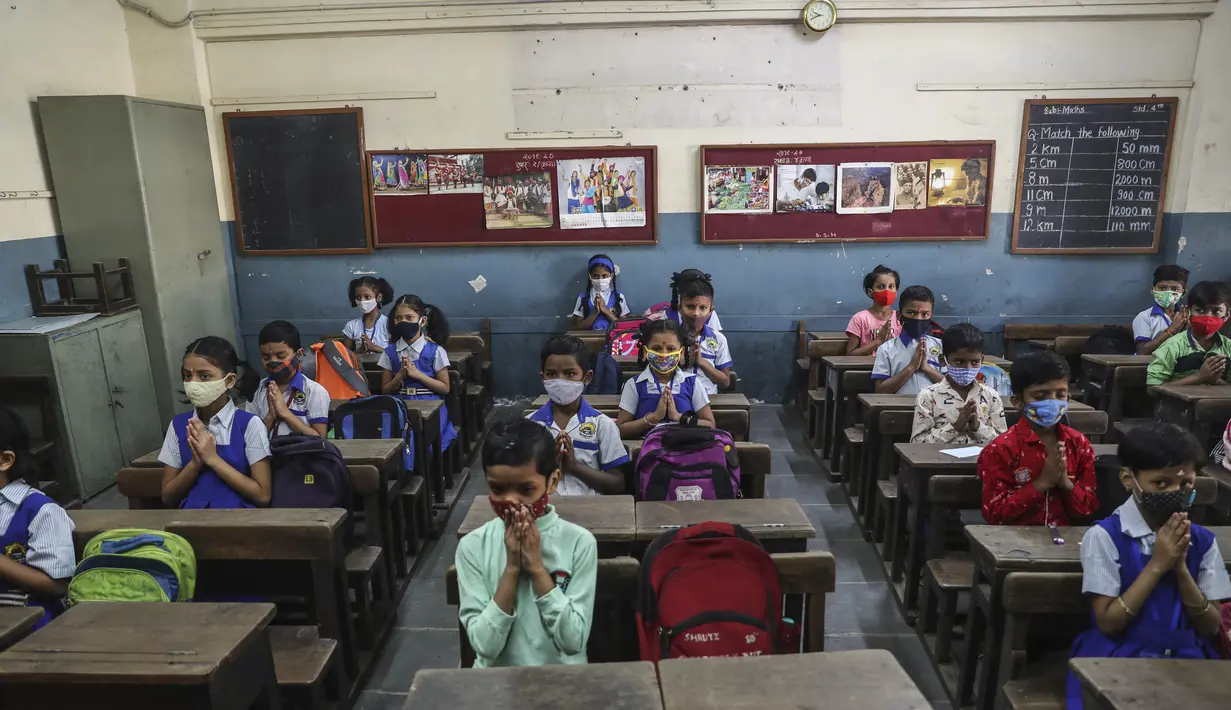 Siswa yang memakai masker berdoa saat bersiap untuk memulai kelas tatap muka di sebuah sekolah di Mumbai, India, Rabu (15/12/2021). Setelah ditutup selama hampir 20 bulan karena pandemi virus corona, sekolah di Mumbai dibuka kembali untuk kelas 1 sampai 7. (AP Photo/Rafiq Maqbool)