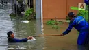 Petugas Sudin Sumber Daya Air (SDA) memunguti sampah-sampah yang tergenang saat banjir di kawasan Kampung Melayu Kecil, Bukit Duri, Jakarta, Selasa (25/2/2020). Banjir tersebut akibat luapan sungai Ciliwung. (merdeka.com/magang/ Muhammad Fayyadh)