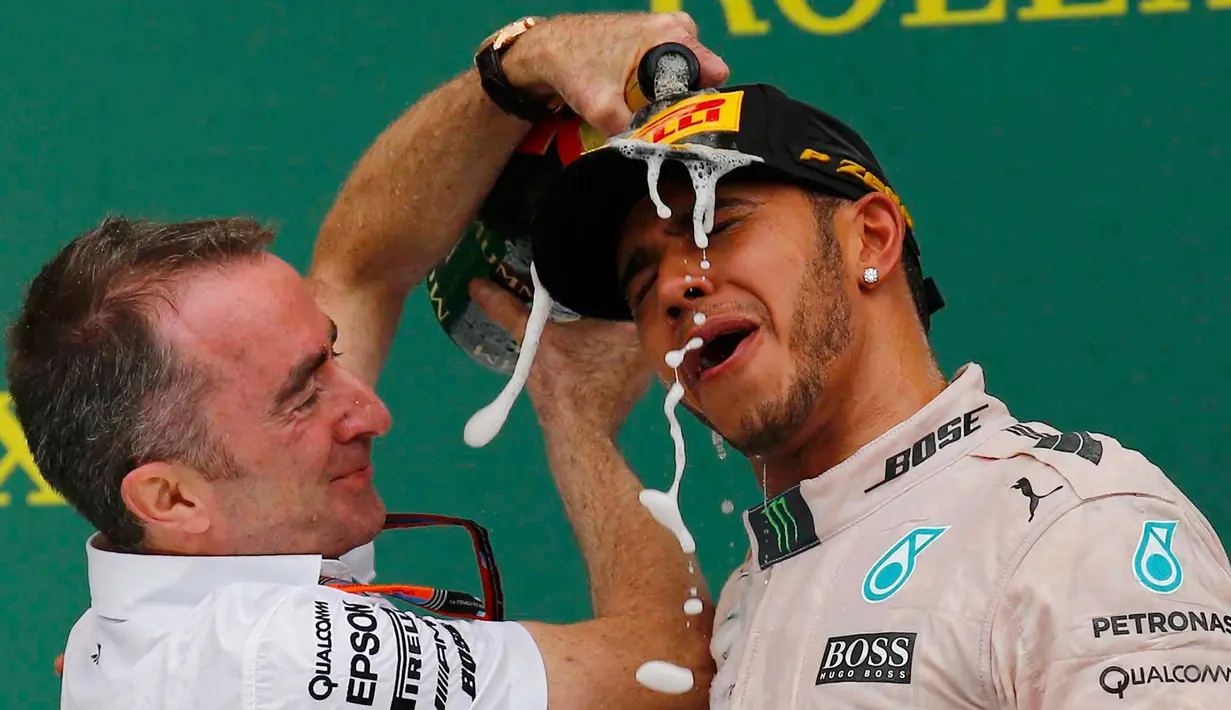Direktur Mercedes, Paddy Lowe menuangkan sampanye ke Lewis Hamilton usai merebut gelar GP F1 di Sirkuit The Americas, Minggu (25/10). Ini merupakan gelar juara dunia ketiga bagi Hamilton setelah sebelumnya diraih pada 2008 dan 2014. (REUTERS/Mike Stone)