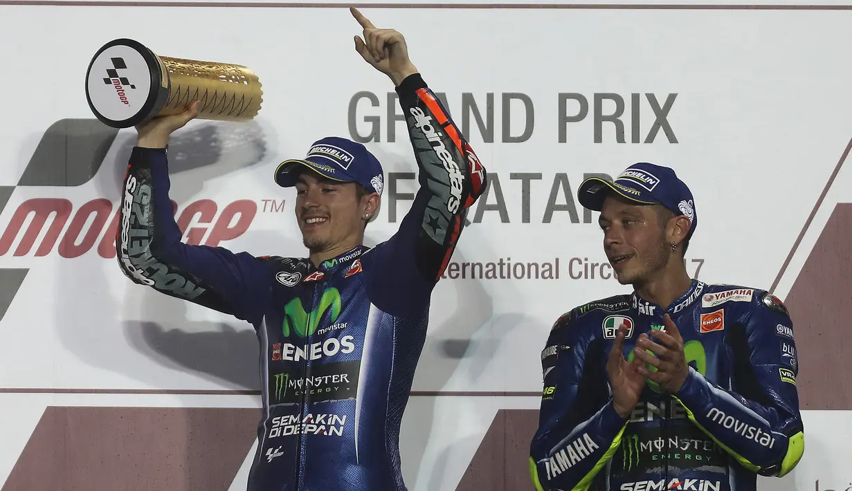 Pembalap Movistar Yamaha, Maverick Vinales bersama rekan setimnya, Valentino Rossi merayakan kemenangannya di atas podium MotoGP Qatar di Sirkuit Losail, Doha, Minggu (26/3). Maverick Vinales keluar sebagai juara MotoGP Qatar. (Karim JAAFAR/AFP)