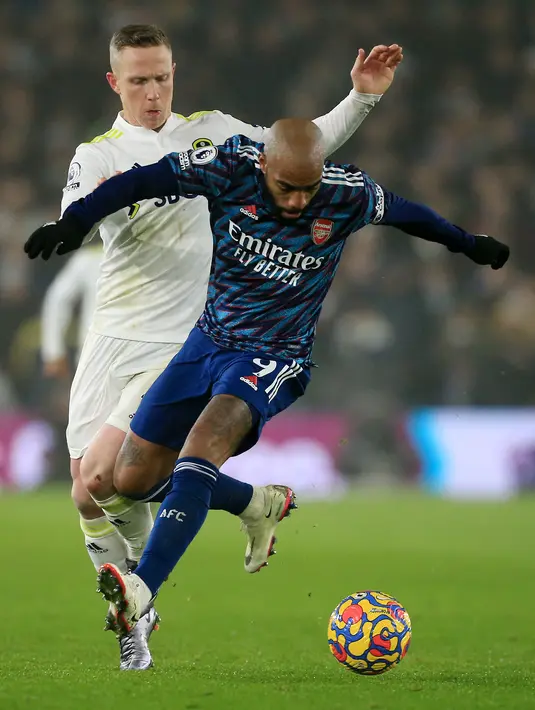 Gelandang Leeds United Adam Forshaw (kiri) bersaing dengan striker Arsenal Alexandre Lacazette (kanan) pada pekan ke-18 Liga Inggris di Stadion Ellan Road, Leeds, Minggu (19/12/2021) dini hari WIB. Arsenal menang 4-1 di kandang Leeds United. (Lindsey Parnaby / AFP)