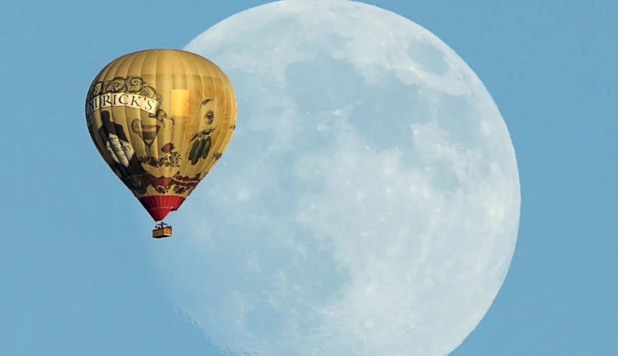 Sebuah balon udara terbang  melewati bulan yang terlihat dilangit California, Amerika Serikat 25 September 2015. (REUTERS/Mike Blake)