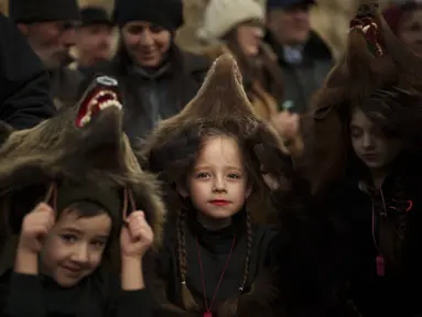 Sofia, 6 tahun, tengah, anggota kelompok beruang tradisional mengambil bagian dalam parade sebelum tampil di festival di Moinesti, Rumania utara, Rabu, 27 Desember 2023. (AP Photo/Vadim Ghirda)