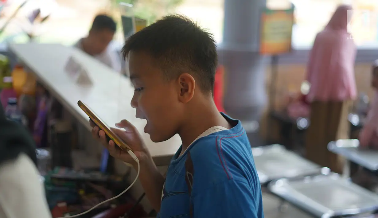Seorang anak berbicara menggunakan ponsel setelah terpisah dari keluarganya di Taman Margasatwa Ragunan, Jakarta, Kamis (6/6/2019). Membeludaknya pengunjung, membuat banyak orang yang memadati pusat informasi untuk mencari anggota keluarga serta barang berharga. (Liputan6.com/Immanuel Antonius)