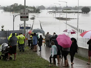 Warga menyaksikan banjir Sungai Hawkesbury di Windsor, barat laut Sydney, New South Wales, Australia (22/3/2021).  Negara bagian New South Wales yang padat penduduknya telah mengeluarkan lebih banyak perintah evakuasi menyusul banjir terburuk dalam beberapa dekade. (AP Photo/Rick Rycroft)