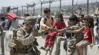 Seorang Marinir dengan Satuan Tugas Udara-Tanah Laut Tujuan Khusus-Komando Pusat Respons Krisis (SPMAGTF-CR-CC) bermain dengan anak-anak yang menunggu untuk diproses selama evakuasi di Bandara Internasional Hamid Karzai di Kabul , Afghanistan (20/8/2021).  (Sgt. Samuel Ruiz/U.S. Marine Corps via AP)