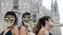 Sejumlah wanita dari Aktivis PETA mengenakan topeng buaya saat menggelar unjuk rasa jelang Milan Fashion Week di Milan Duomo Square, Italia, Selasa (21/2). Mereka mengecam produk fashion yang terbuat dari kulit hewan. (AP Photo/Antonio Calanni)