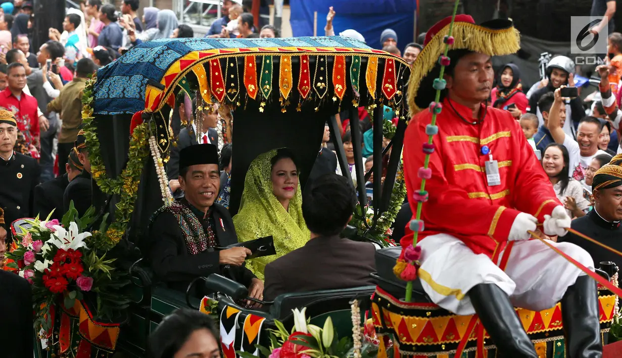 Presiden Joko Widodo bersama Ibu Negara Iriana saat membagikan kaus di atas kereta kencana saat kirab resepsi pernikahan Kahiyang Ayu-Bobby Nasution di Kota Medan, Sumatera Utara, Minggu (26/11). (Liputan6.com/Johan Tallo)