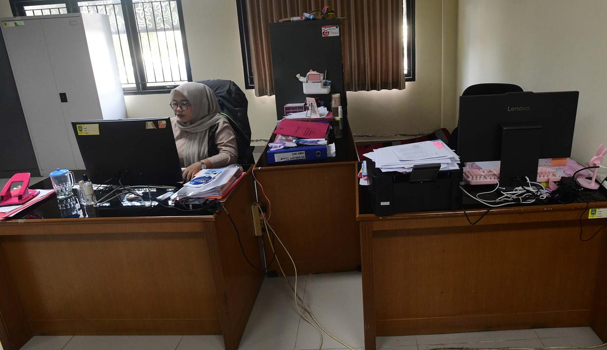 Masing-masing instansi dipersilakan mengatur sistem serta pola kerja dengan dukungan teknologi agar produktivitas tidak terganggu. Tampak dalam foto, pegawai bekerja di depan komputer dengan beberapa meja kursi yang kosong saat penerapan Work From Home (WFH) bagi Aparatur Sipil Negara (ASN) di kantor Kecamatan Limo, Depok, Jawa Barat, Jumat (10/4/2026). (merdeka.com/Arie Basuki)