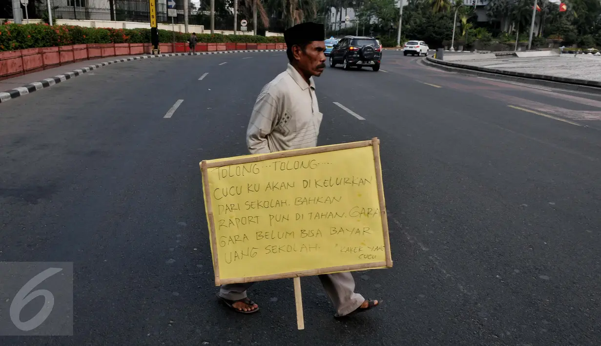 Syaripudin Dodo (59) melakukan aksi dengan membawa poster di Bundaran HI, Jakarta, Kamis (30/7/2015). Kakek ini meminta pertolongan pengguna jalan untuk membiayai sekolah cucunya di Perguruan Islam Al Masthuriyah Sukabumi. (Liputan6.com/Johan Tallo)