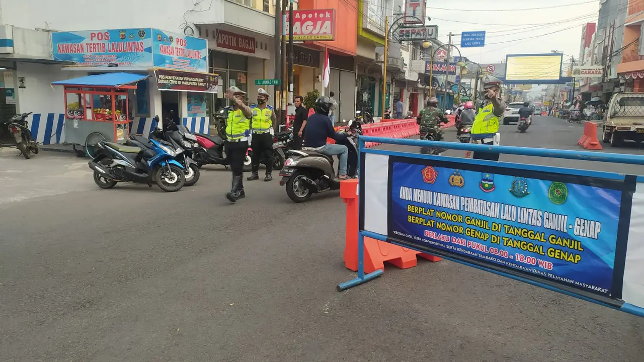 Sejumlah petugas kepolisian tengah mengamanka sejumlah rute di pusat perkotaan Jl. Jenderal Ahmad Yani, Garut, Jawa Barat dalam penerapan sistem ganjil-genap saat PPKM level 3 di Garut.