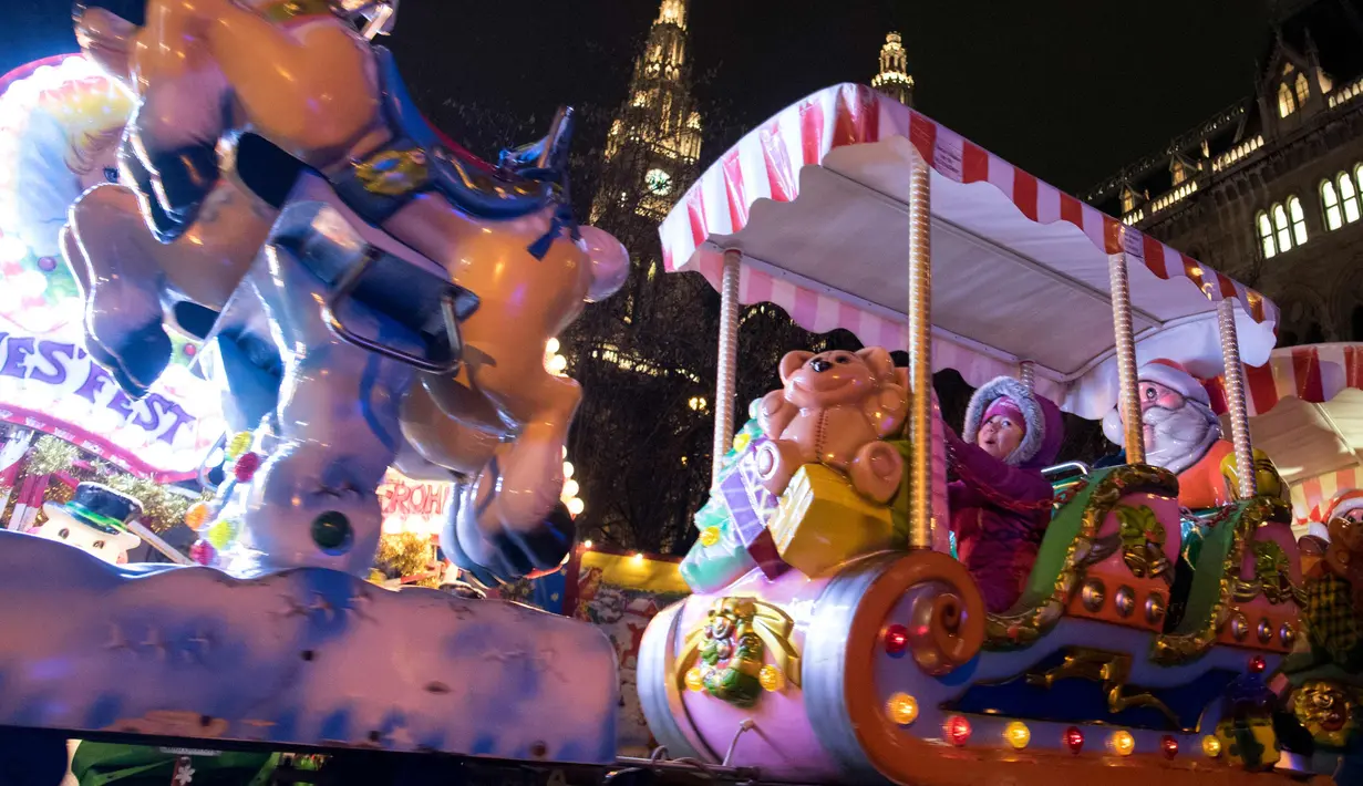 Seorang anak menaiki kereta di sebuah pasar Natal di luar Balai Kota di Wina, Austria (5/12). (AFP Photo/Joe Klamar)