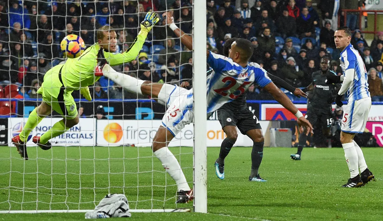 Gelandang Chelsea, Willian berhasil mencetal gol melewati kiper Huddersfield Town, Jonas Lossi pada lanjutan pertandingan Premier League di Stadion The John Smith's, Selasa (12/12). Chelsea menaklukkan Huddersfield Town dengan skor 3-1. (Oli SCARFF / AFP)