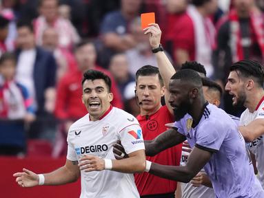 Bek Sevilla, Marcos Acuna didorong oleh bek Real Madrid Antonio Rudiger setelah mendapat kartu merah dan dikeluarkan dari lapangan pada pekan ke-37 La Liga, Minggu (28/5/2023) dini hari WIB. (AP Photo/Jose Breton)