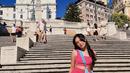 Beby Tsabina saat berpose Spanish Steps, Roma. Ia tampil cantik dengan busana serba pink sambil membawa tas serta sepatu warna putih. (Instagram/bebytsabin)