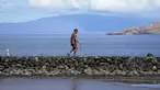 Vicente Ruboi berjalan setelah kebakaran hutan yang melanda Maui di sepanjang tembok laut, di Kihei, Hawaii,  Selasa, 15 Agustus 2023. (AP Photo/Rick Bowmer)