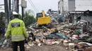 Petugas Polisi berjaga di lokasi reruntuhan bangunan PHD, Kota Bekasi ketika alat berat membersihkan reruntuhan, Minggu (23/10). Akibat ledakan tersebut Jalan Raya Hankam, Jatimelati, Pondokmelati ditutup. (Liputan6.com/Yoppy Renato)