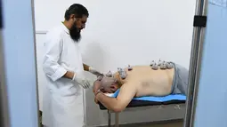 Spesialis melakukan pengobatan hijama atau terapi bekam basah kepada pasien di sebuah klinik di Ajman, Uni Emirat Arab, Kamis (15/8/2019). Hijama adalah teknik pengobatan dengan jalan membuang darah kotor (racun yang berbahaya) dari dalam tubuh melalui permukaan kulit. (KARIM SAHIB/AFP)