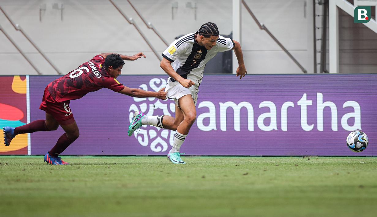 <p>Pemain Timnas Jerman U-17, Paris Brunner (kanan)&nbsp;mendaptkan gangguan dari&nbsp;pemain Timnas Venezuela U-17, Rai Hidalgo dalam laga pamungkas Grup F Piala Dunia U-17 2023 yang berlangsung di Jakarta International Stadium (JIS), Jakarta, Sabtu (18/11/2023). (Bola.com/Bagaskara Lazuardi)</p>