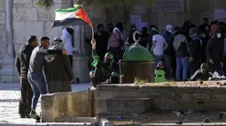 Seorang pengunjuk rasa Palestina mengibarkan bendera Palestina saat bentrokan dengan pasukan keamanan Israel di Kompleks Masjid Al Aqsa, Kota Tua Yerusalem, 15 April 2022. (AP Photo/Mahmoud Illean)