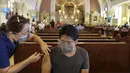 Petugas kesehatan menyuntik seorang pria dengan vaksin COVID-19 AstraZeneca di dalam gereja Paroki Hati Kudus Yesus di Quezon City, Filipina, Senin (17/5/2021). Sempat ditangguhkan, Filipina melanjutkan penggunaan vaksin AstraZeneca pada penduduk berumur di bawah 60 tahun. (AP Photo/Aaron Favila)