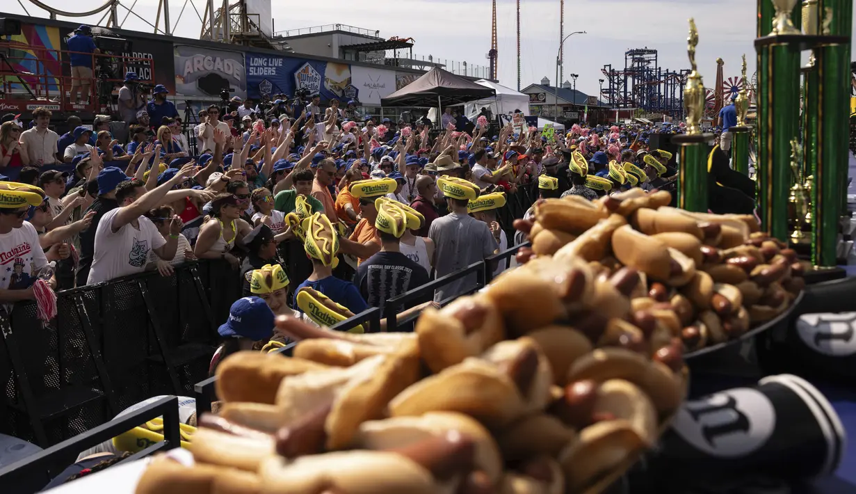 Acara Hari Kemerdekaan yang meriah ini mendatangkan ribuan orang ke Coney Island, New York, pada hari Selasa untuk menyaksikan para peserta lomba yang kompetitif melahap sebanyak mungkin hot dog hanya dalam waktu 10 menit. (AP Photo/Yuki Iwamura)