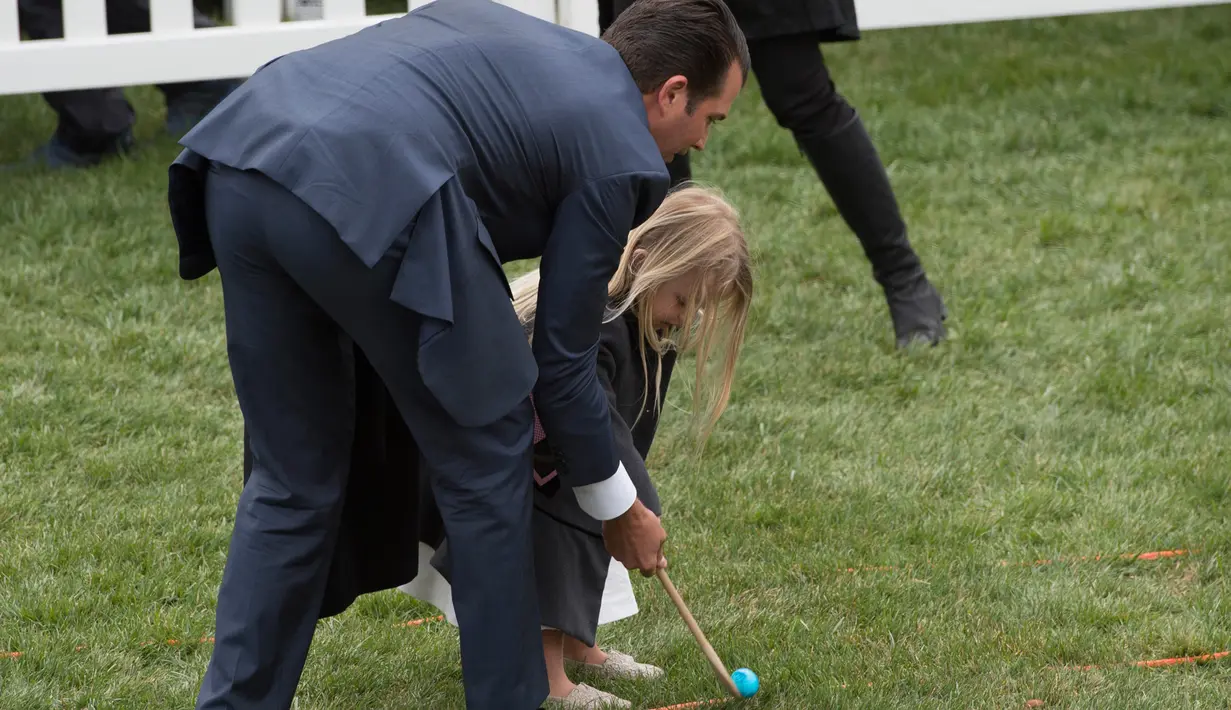 Donald Trump, Jr membantu putrinya Chloe Sophia Trump saat mengikuti lomba menggelindingkan telur di halaman Gedung Putih, Washington (4/2). (AFP Photo / Andrew Caballero-Reynolds)