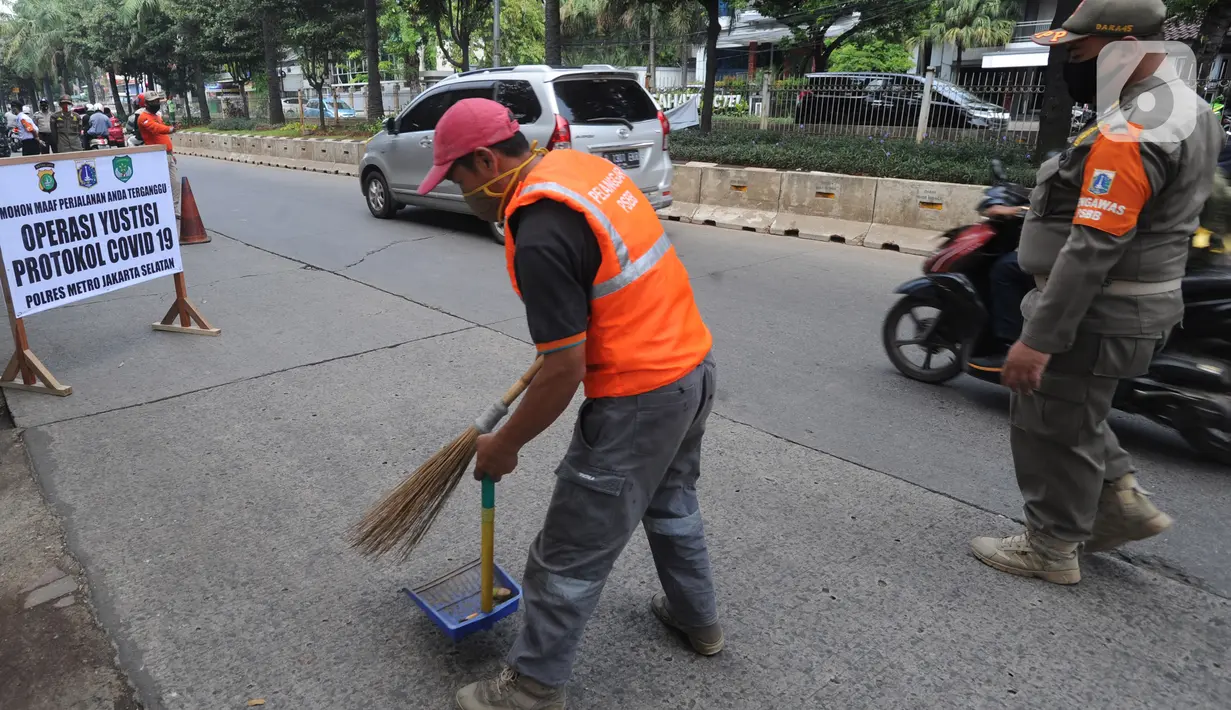 Seorang pelanggar menyapu jalanan saat terjaring Operasi Yustisi Protokol COVID-19 di Jati Padang, Jakarta Selatan, Kamis (17/9/2020). Operasi itu untuk menegakan penerapan protokol kesehatan, terutama dalam penggunaan masker guna menekan penyebaran virus corona. (merdeka.com/Arie Basuki)