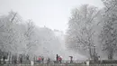 Orang-orang berjalan saat salju turun di Taman Retiro di pusat kota Madrid (7/1/2021). Sebagian Spanyol utara telah mengalami kondisi musim dingin selama beberapa hari, dengan suhu di bawah nol dan hujan salju di kota-kota seperti Vitoria di Basque Country. (AFP/Gabriel Bouys)