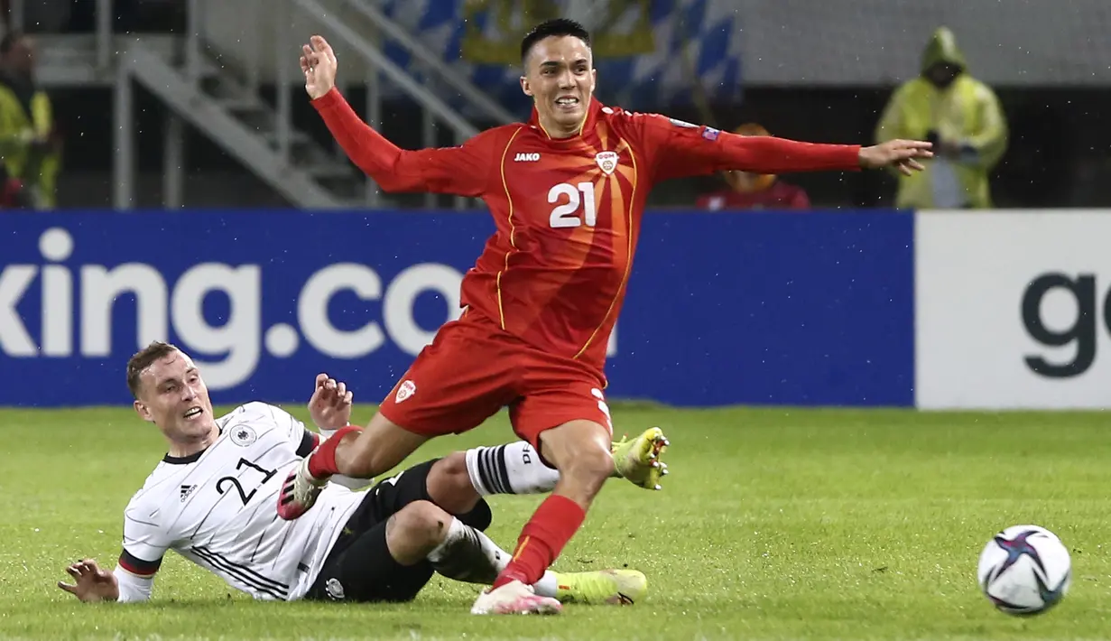 Bek Jerman David Raum menghentikan gelandang Makedonia Utara Tihomir Kostadinov pada lanjutan Kualifikasi Piala Dunia 2022 zona Eropa Grup J di Tose Proeski National Arena, Selasa (12/10/2021) dini hari WIB. Jerman menghajar Makedonia Utara empat gol tanpa balas. (AP Photo/Boris Grdanoski)