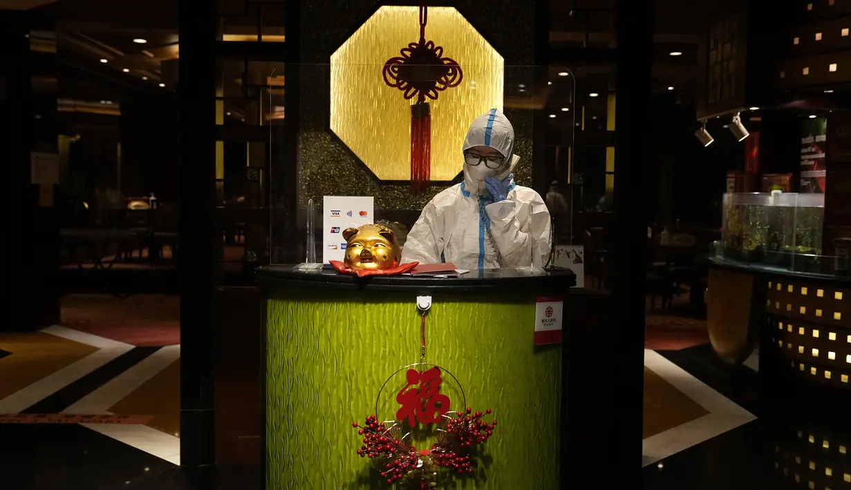 Mengenakan pakaian pelindung diri atau hazmat, seorang resepsionis restoran berbicara melalui telepon di Hotel Shangri-La pada Olimpiade Musim Dingin 2022, 16 Februari 2022, di Beijing. (AP Photo/Jae C.Hong)