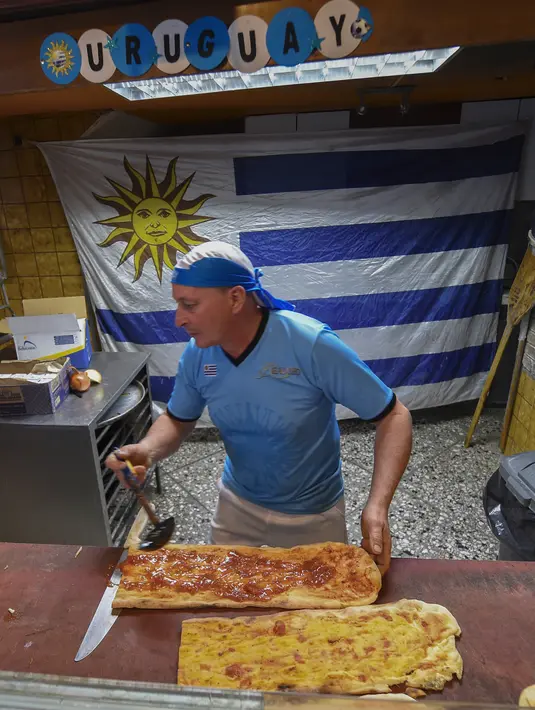 Koki membuat makanan di sebuah bar di Montevideo (4/7). Warga Uruguay antusias mempersiapkan untuk mendukung negaranya bertanding melawan Prancis pada babak 8 besar Piala Dunia 2018 di Rusia. (AFP Photo/Miguel Rojo)