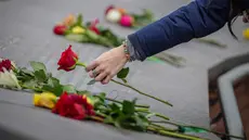 Kelli Muster dari Santa Rosa, California meletakkan bunga mawar merah di Columbine Memorial di Clement Park pada peringatan 25 tahun penembakan di sekolah tersebut pada 20 April 2024 di Littleton, Colorado. (Marc Piscotty/Getty Images North America/Getty Images via AFP)