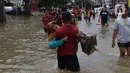 Seorang nenek digendong saat melintasi banjir yang menggenangi Jalan KH Hasyim Ashari, Tangerang, Banten, Kamis (2/1/2020). Banjir yang menggenangi jalan penghubung Jakarta- Tangerang tersebut mulai surut dan sudah bisa dilintasi pejalan kaki. (Liputan6.com/Angga Yuniar)